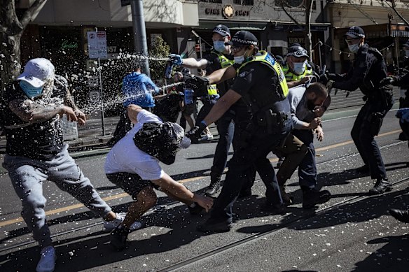 Police use capsicum spray to subdue protesters near state parliament on Spring Street in Melbourne’s CBD.