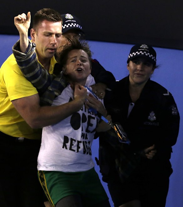 A political protester is taken away from Rod Laver Arena by a security guard and police  during the men's singles final between Andy Murray of Britain and Novak Djokovic of Serbia at the Australian Open tennis championship in Melbourne, Australia, Sunday, Feb. 1, 2015.