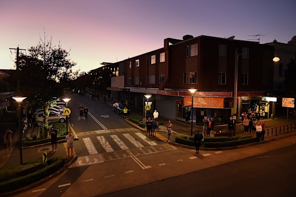 People listen to bugler Sarah Brown as she plays The Last Post from the balcony of The Royal Hotel on Norton Street in Leichhardt at dawn on ANZAC Day. 