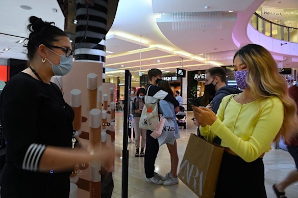 Emma Davaa, right, checks in to enter the Sephora store in Westfield Bondi Junction shopping centre on the first day of relaxed COVID-19 restrictions for fully vaccinated people.