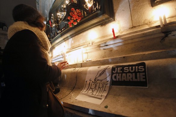 A woman lays a candle during a gathering at the Place de la Republique.