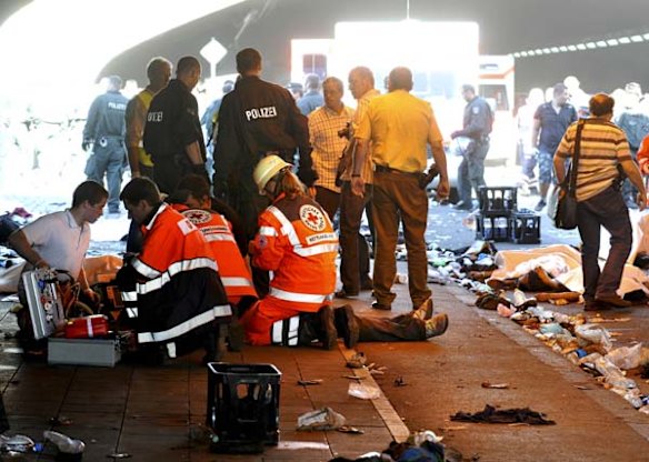 Rescue workers attend to an injured person as firefighters and police officers stand beside casualties after a stampede in a tunnel during the Love Parade festival in Duisburg, western Germany.