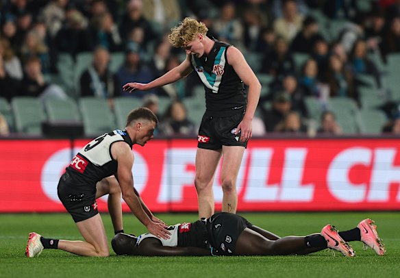 Big hit: Jacob Wehr and Balyn O’Brien rush to the aid of Aliir Aliir after the latter was hit.