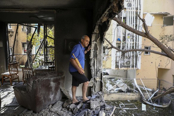 A member of Sror family inspect the damage of their apartment after being hit by a rocket fired from the Gaza Strip over night, in Petah Tikva, central Israel, Thursday, May 13, 2021.
