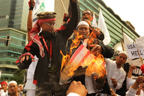 Islamic Defenders Front (FPI) protestors burns a poster of a US flag as hundreds gather for anti US protests at the Bunderan Hotel Indonesia traffic circle in Central Jakarta, Indonesia.