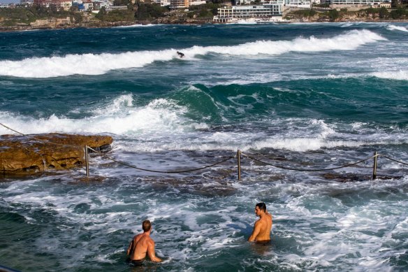 People enjoying a cold swim and watching the big surf at Bondi Beach in winter.