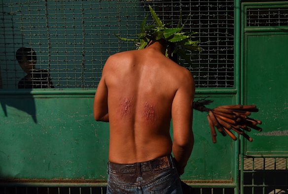 A man carries out the decades long tradition of self flagellaion, whipping their backs with 25 bamboo sticks.