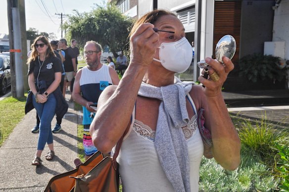 A woman does her mascara whilst waiting in line at Brookvale Centrelink. March 25, 2020