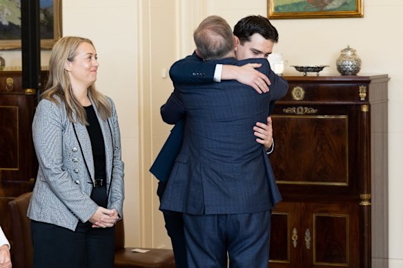 Prime Minister Anthony Albanese's partner Jodie Haydon smiles as he embraces his son Nathan during the swearing in ceremony.