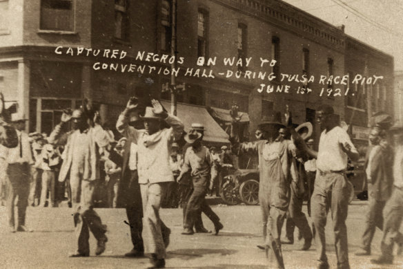 A group of Black men are marched past the corner of 2nd and Main Streets in Tulsa, Okla., under armed guard during the Tulsa Race Massacre on June 1, 1921.