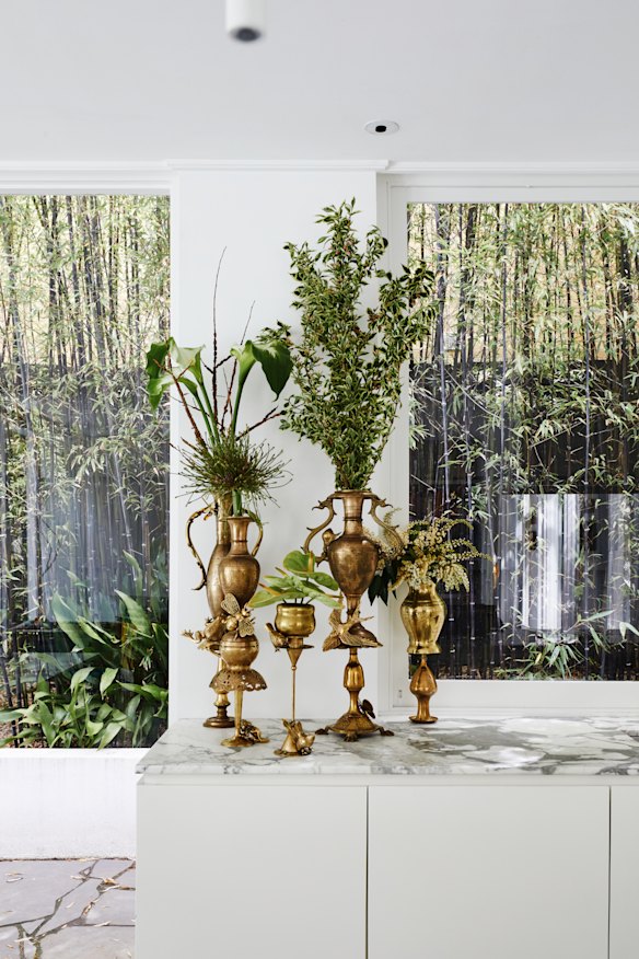 On a marble kitchen bench are brass vessels Stanford designed for florist Flowers Vasette. She also created the “cluster” door handles (above right) for its stores.