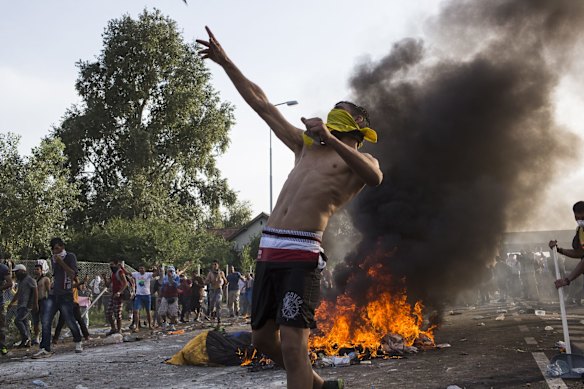A protesting refugee throws projectiles at Hungarian police.