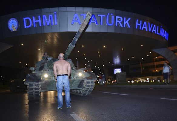 A man stands in front of a tank in the entrance to Istanbul's Ataturk airport.