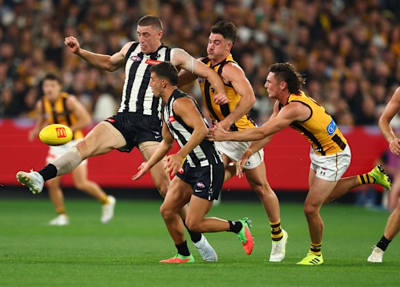 Putting the boot in: Magpies ruckman chases a kick against Hawthorn on Thursday night.