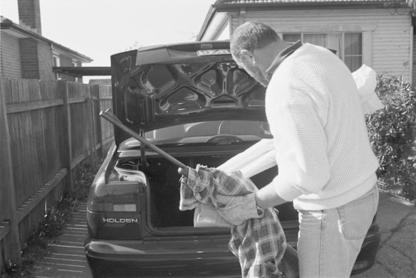 A detective places a rilfle that was found in the boot.