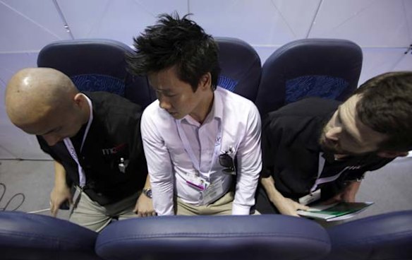 Melvyn Koh (C) tries out Italian company Aviointeriors' new aircraft 'Skyrider' seat.