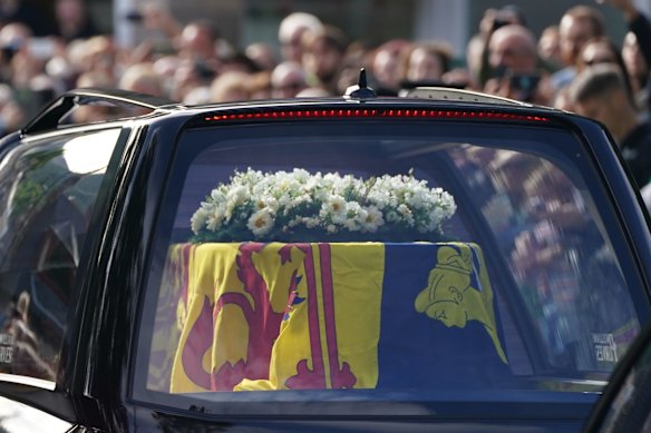 Members of the public line the streets in Ballater, Scotland, as the hearse carrying the coffin of Queen Elizabeth II passes through as it makes its journey to Edinburgh from Balmoral in Scotland, Sunday, Sept. 11, 2022. The Queen's coffin will be transported Sunday on a journey from Balmoral to the Palace of Holyroodhouse in Edinburgh, where it will lie at rest before being moved to London later in the week. (Andrew Milligan/PA via AP)