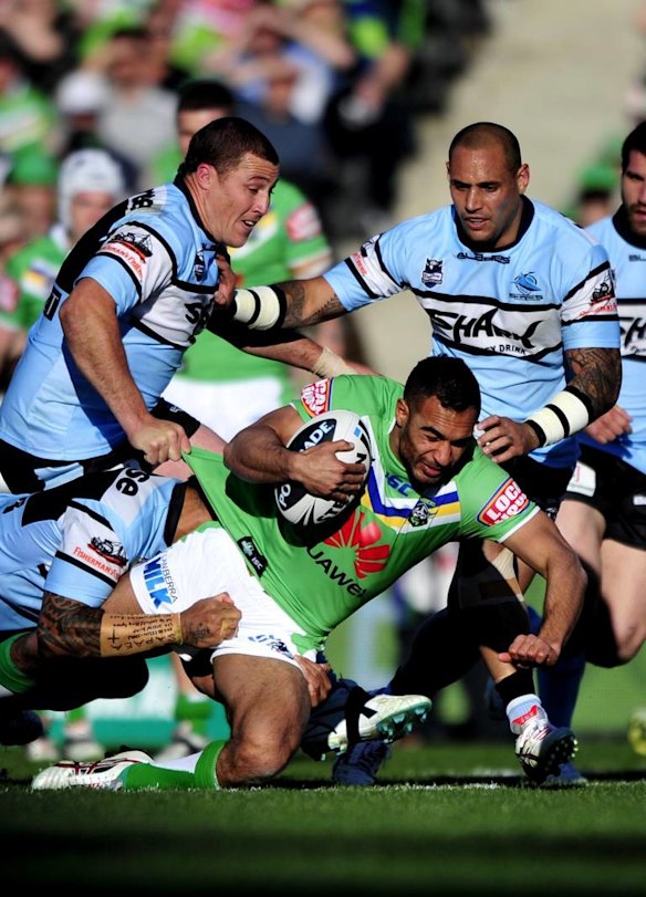 Reece Robinson is tackled by Sharks players Bryce Gibbs and Jeremy Smith.