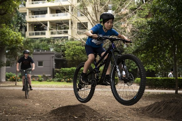 A group of kids having fun jumping their bikes, in Rushcutters bay Park.