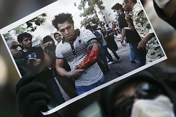 A masked demonstrator holds a photograph during a protest in support of defeated Iranian presidential candidate Mirhossein Mousavi in front of the Iranian Consulate in Istanbul June 21, 2009.