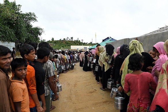 Rohingya refugees queue for a meal provided by a Turkish aid agency at a food distribution site.