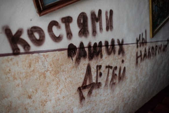 Writing left by Russian soldiers is seen on the walls of a local cultural center in Novyi Bykiv. The writing says, 'We will feed the bones of your children to dogs'.