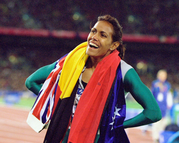 Cathy Freeman celebrates with the Australian and Indigenous flags.