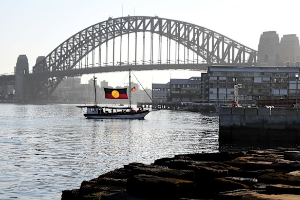 The ceremonial flame arrives by boat during the Australia Day Wugulora Morning Ceremony.