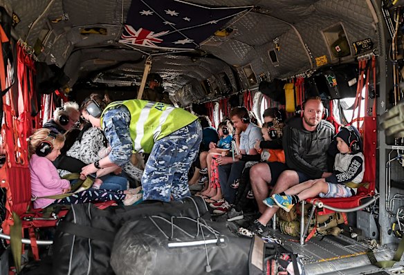 Families with small children and babies are evacuated from Mallacoota on Sunday. 
