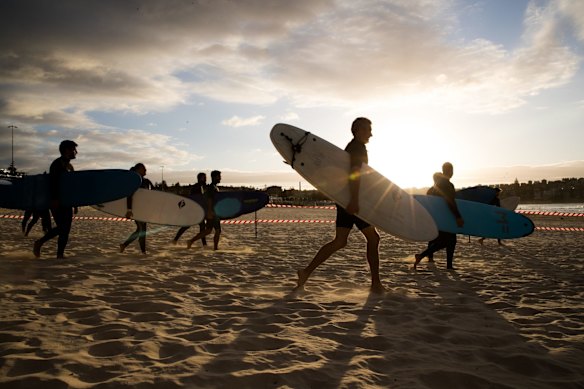 Surfers race to the water at Bondi beach.