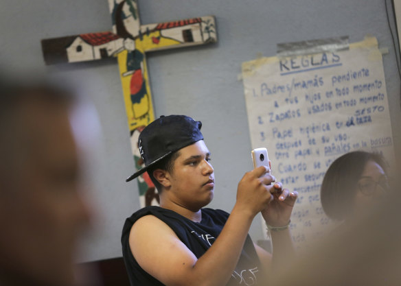 James, 14, takes a picture of his mother, Joselaine, as she speaks.
