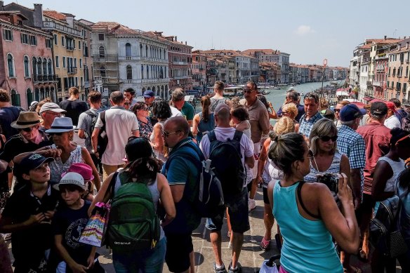 Tourists stand on the Rialto Bridge in Venice. 