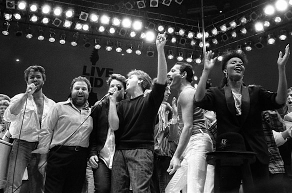 In this July 13, 1985, file photo, from left, George Michael of Wham!, concert promoter Harvey Goldsmith, Bono of U2, Paul McCartney, concert organizer Bob Geldof and Freddie Mercury of Queen join in the finale of the Live Aid famine relief concert, at Wembley Stadium, London.