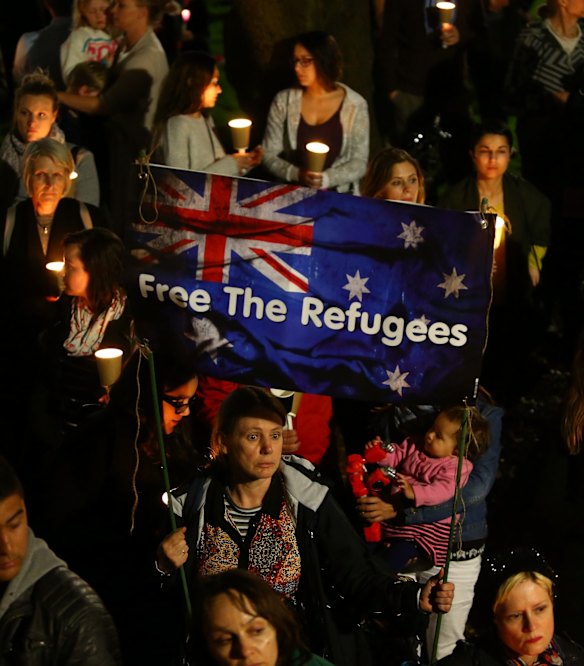 People hold candles and signs up in support of refugees on September 7, 2015 in Sydney, Australia.