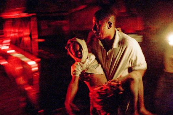 A man carries an injured child outside Hotel Villa Creole.