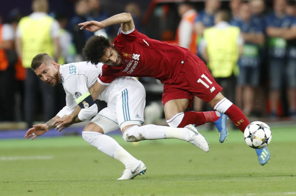 Real Madrid's Sergio Ramos, left, hooks his arm around Liverpool's Mohamed Salah's and pulls him down. 