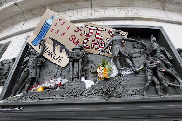 A placard with a news cartoon by French cartoonist Plantu is seen placed amongst other tributes on the statues at the Place de la Republique in Paris, January 10, 2015, after an attack on the offices of French satirical newspaper Charlie Hebdo earlier this week. 