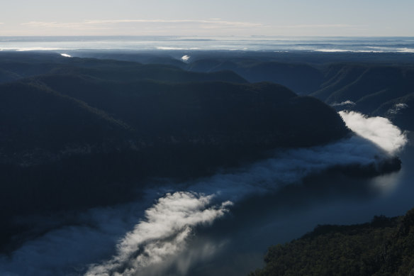 Lake Burragorang, partly shrouded in cloud, sits behind Warragamba Dam. It went from 42 per cent full to spilling within four months, with most of the increase coming from a single rain event in February.