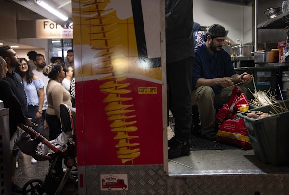 A vendor peels onions at the back of his stall.