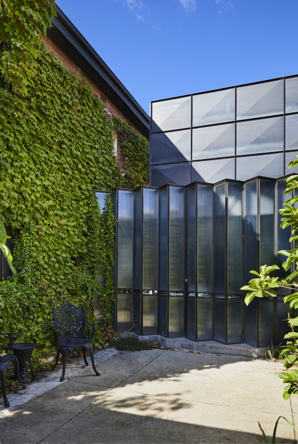 The striking extension of steel and fluted glass creates a dramatic juxtaposition to the original 1930s brick building and its cladding of Boston ivy.