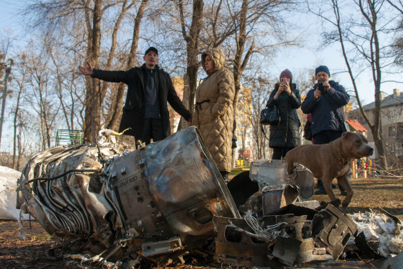 People stand next to fragments of military equipment on the street in the aftermath of an apparent Russian strike in Kharkiv, Ukraine on Thursday.