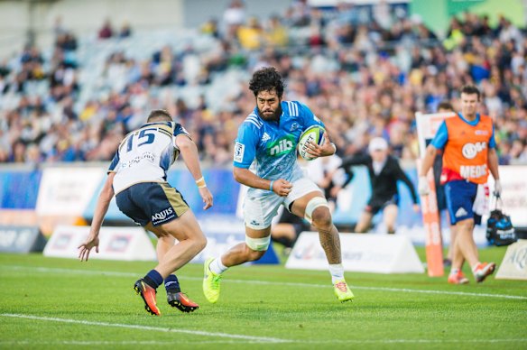 Brumbies fullback Tom Banks tries to stop a charging run by Blues' No.8 Akira Ioane. 