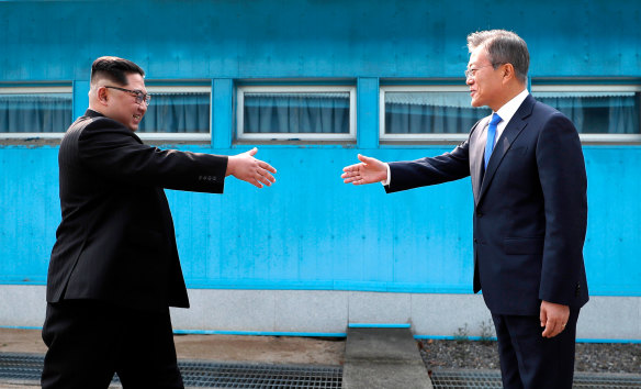 North Korean leader Kim Jong Un, left, prepares to shake hands with South Korean President Moon Jae-in over the military demarcation line.