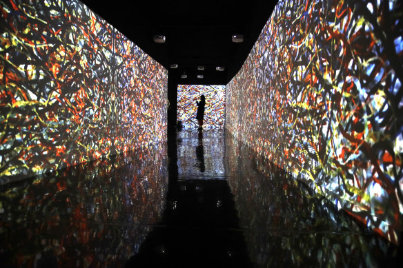 A visitor stands among the projections of Jackson Pollock paintings during a preview of the exhibition "Pollock and the school of NY" in Rome.