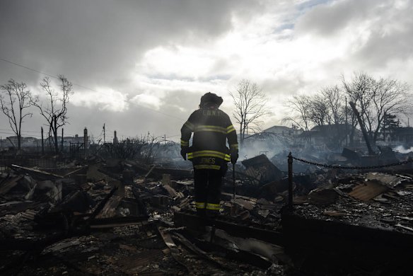 A firefighter walks through the remains of some of the dozens of homes destroyed by fire in Breezy Point in the Queens borough of New York