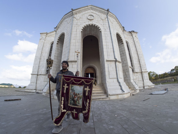 A man carries out a banner from the Holy Saviour Cathedral damaged by shelling during a military conflict, in Shushi, in the self-proclaimed Republic of Nagorno-Karabakh.
