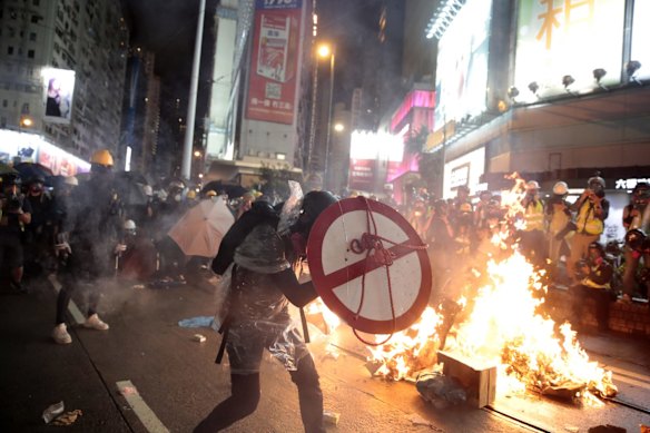 A protestor uses a shield to cover himself as he faces policemen in Hong Kong, Saturday, Aug. 31, 2019. 