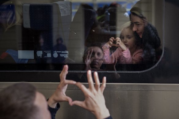 Ukrainian Nicolai, 41, says goodbye to his daughter Elina, 4, and wife Lolita, aboard a train bound for Poland as they flee the war at the railway station in Lviv.