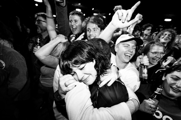 Labor supporters embrace each other as election results begin rolling in on television screens.