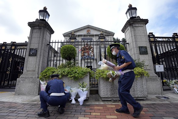 Security guards move condolence flowers outside the British Embassy following the death of Queen Elizabeth II, Friday, Sept. 9, 2022, in Tokyo.